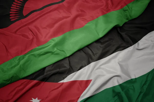 Acenando bandeira colorida da Jordânia e bandeira nacional do Malawi . — Fotografia de Stock
