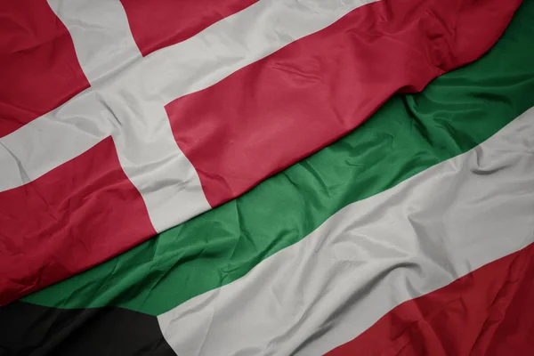 Ondeando colorida bandera de kuwait y bandera nacional de denmark . —  Fotos de Stock
