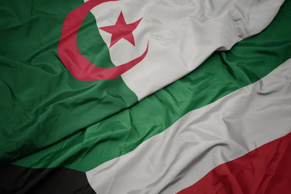 Machając kolorowe flagi Kuwejtu i flagi narodowej Algierii. — Zdjęcie stockowe