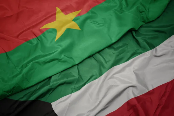 Ondeando colorida bandera de kuwait y bandera nacional de burkina faso . — Foto de Stock