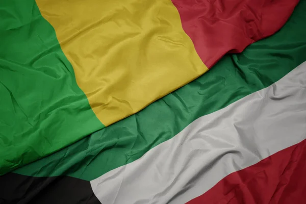 Ondeando colorida bandera de kuwait y bandera nacional de mali . — Foto de Stock