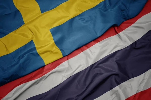 Zwaaiende kleurrijke vlag van Thailand en de nationale vlag van Zweden. — Stockfoto
