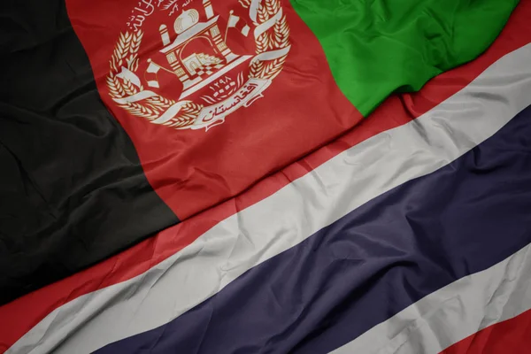 Ondeando colorida bandera de Tailandia y bandera nacional de Afganistán . — Foto de Stock
