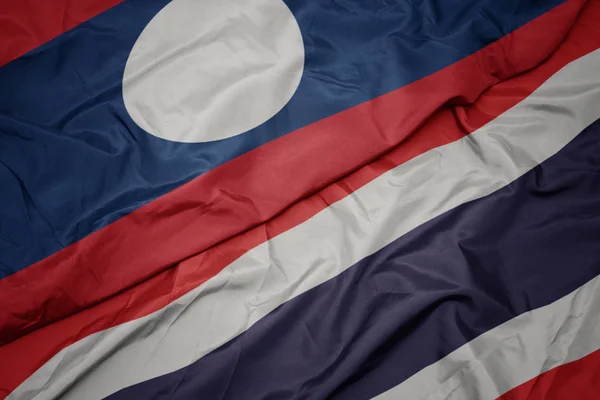 Falujące kolorowe flagi Tajlandii i flagi narodowej Laosu. — Zdjęcie stockowe