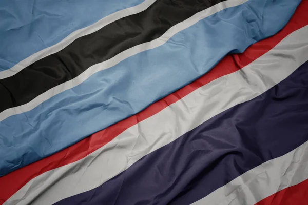 Mávající barevná vlajka Thajska a národní vlajka Botswany. — Stock fotografie