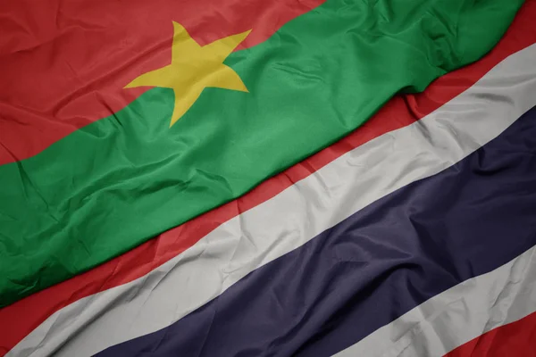 Ondeando colorida bandera de Tailandia y bandera nacional de Burkina faso . — Foto de Stock