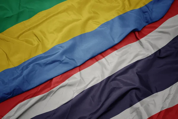 Ondeando colorida bandera de Tailandia y bandera nacional de Gabón . — Foto de Stock