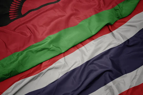 Ondeando colorida bandera de Tailandia y bandera nacional de Malawi . — Foto de Stock