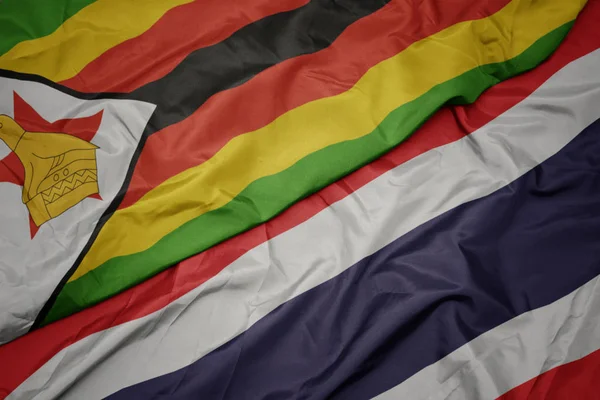 Agitant drapeau coloré de Thaïlande et drapeau national de zimbabwe . — Photo