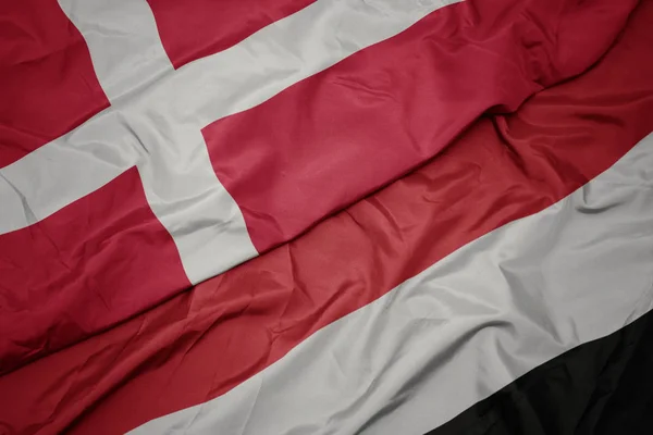 Mávat barevnou vlajku Jemenu a národní vlajkou Dánska. — Stock fotografie