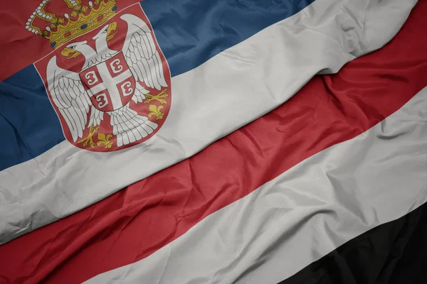 Agitant le drapeau coloré du Yémen et le drapeau national de la Serbie . — Photo
