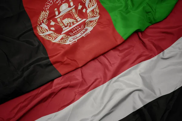 Ondeando colorida bandera de yemen y bandera nacional de afghanistan . — Foto de Stock