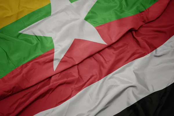 Schwenken bunte Flagge des Jemen und Nationalflagge von Myanmar. — Stockfoto