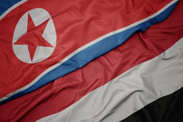 Mávající barevná vlajka Jemenu a národní vlajka Severní Koreje. — Stock fotografie