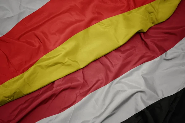 Acenando bandeira colorida do Iêmen e bandeira nacional da ossétia do sul . — Fotografia de Stock