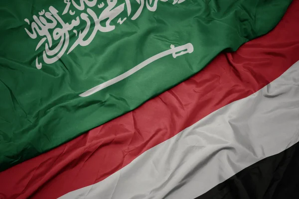 Acenando bandeira colorida do Iêmen e bandeira nacional da Arábia Saudita . — Fotografia de Stock