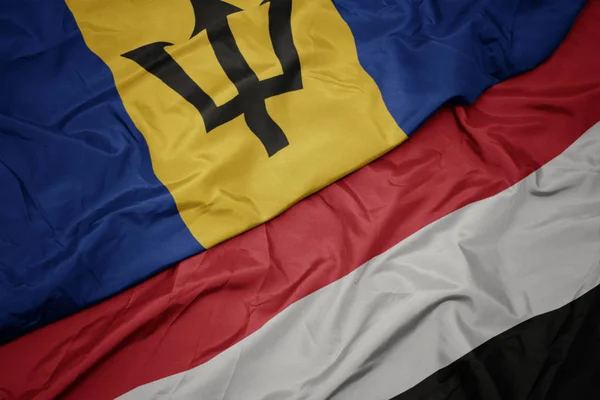 Waving colorful flag of yemen and national flag of barbados. — Stock Photo, Image