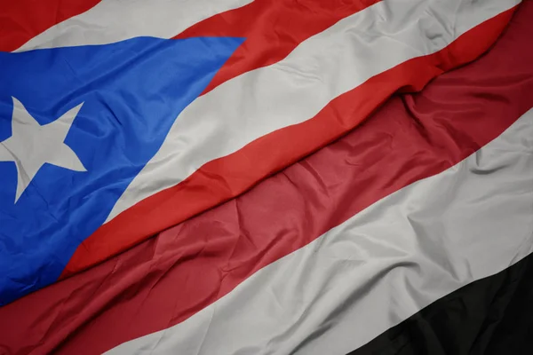Zwaaiende kleurrijke vlag van Jemen en de nationale vlag van Puerto Rico. — Stockfoto