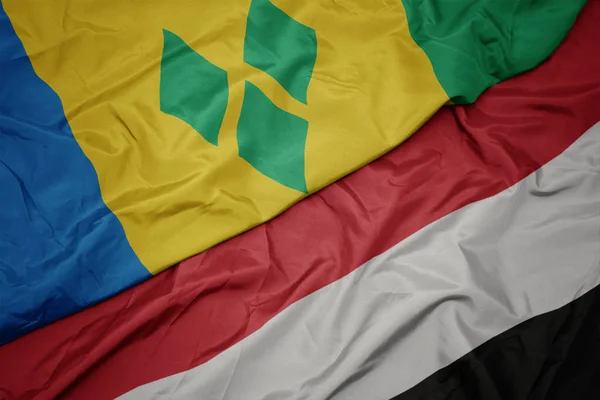 Zwaaiende kleurrijke vlag van Jemen en de nationale vlag van Saint Vincent en de Grenadines. — Stockfoto