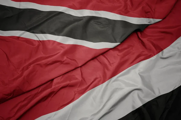 Ondeando colorida bandera de yemen y bandera nacional de trinidad y tobago — Foto de Stock