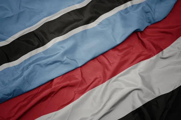 Ondeando colorida bandera de yemen y bandera nacional de botswana . — Foto de Stock