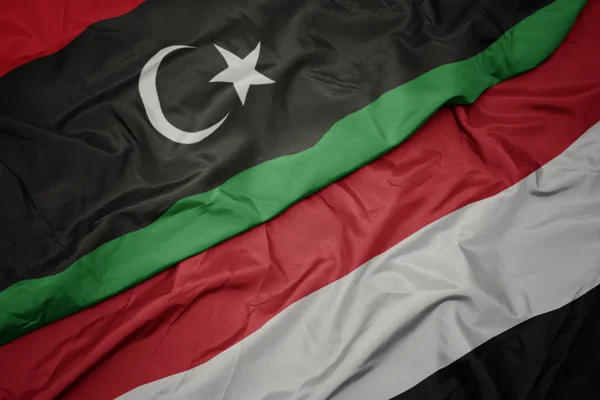 Waving colorful flag of yemen and national flag of libya. — Stock Photo, Image