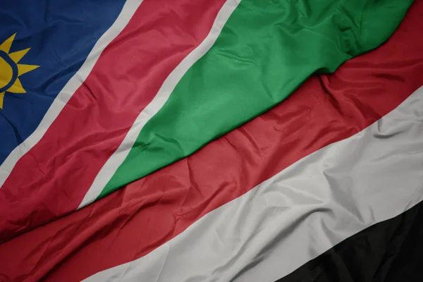 Acenando bandeira colorida do Iêmen e bandeira nacional da Namíbia . — Fotografia de Stock