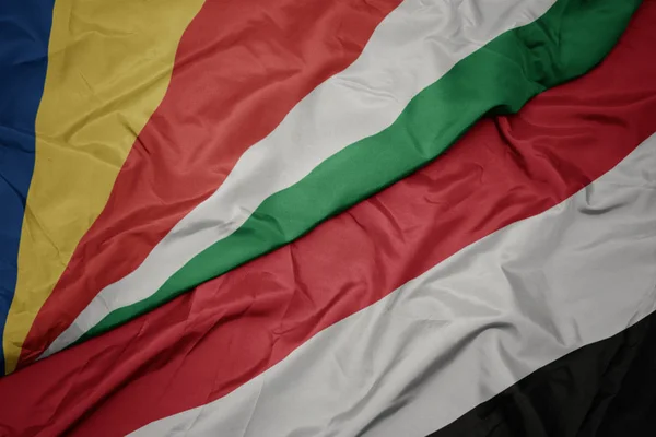 Ondeando colorida bandera de yemen y bandera nacional de seychelles . — Foto de Stock