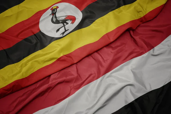 Acenando com bandeira colorida do Iêmen e bandeira nacional do Uganda . — Fotografia de Stock