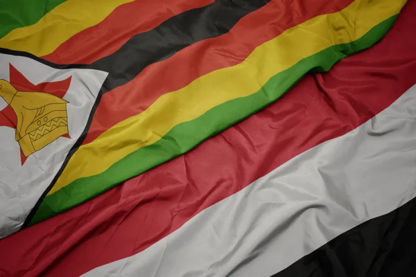 waving colorful flag of yemen and national flag of zimbabwe.