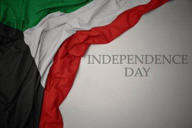 metin bağımsızlık günü ile gri bir arka plan üzerinde Kuveyt renkli ulusal bayrak sallayarak.