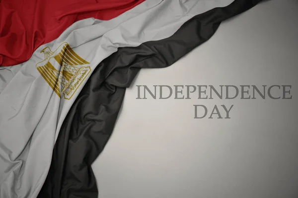 Integetett színes nemzeti zászló Egyiptom szürke háttér szöveges függetlenség napja. — Stock Fotó