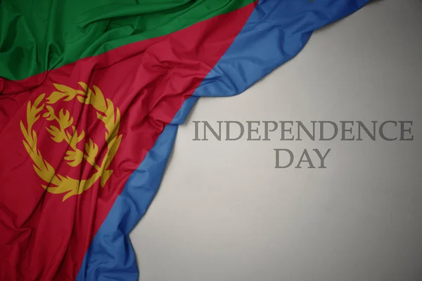 Schwenken bunte Nationalflagge von Eritrea auf grauem Hintergrund mit Text Unabhängigkeitstag. — Stockfoto