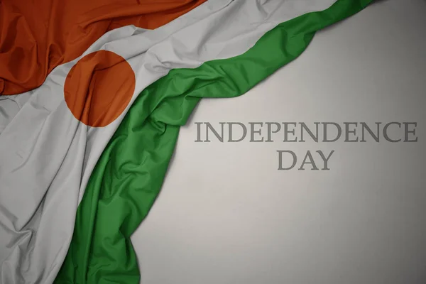 Waving colorful national flag of niger on a gray background with text independence day. — Stock Photo, Image