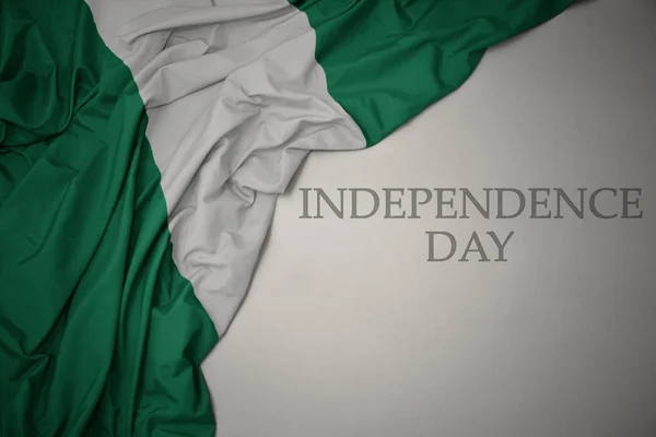 Agitant drapeau national coloré de nigeria sur un fond gris avec le jour de l'indépendance du texte . — Photo