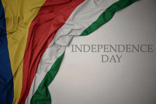 Κυματιστό χρώμα της εθνικής σημαίας των Σεϋχελλών σε γκρίζο φόντο με την ημέρα ανεξαρτησίας του κειμένου. — Φωτογραφία Αρχείου