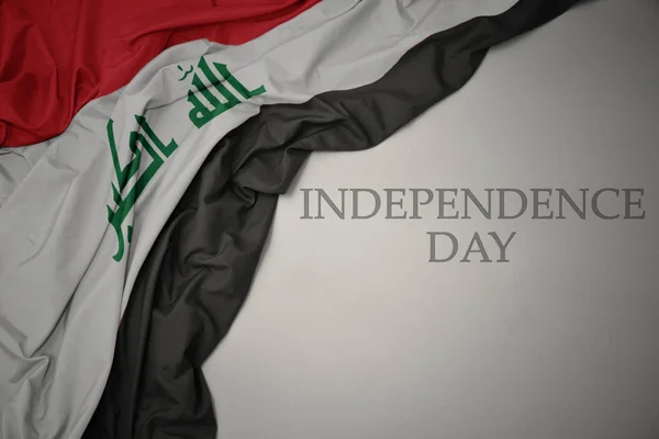 Ondeando colorida bandera nacional de Irak sobre un fondo gris con el día de la independencia del texto . —  Fotos de Stock