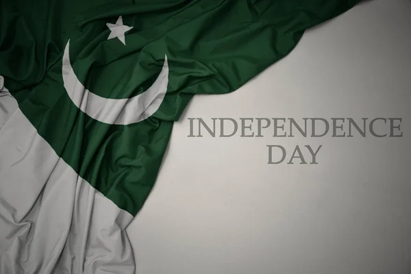 Ondeando colorida bandera nacional de Pakistán sobre un fondo gris con el día de la independencia del texto . — Foto de Stock