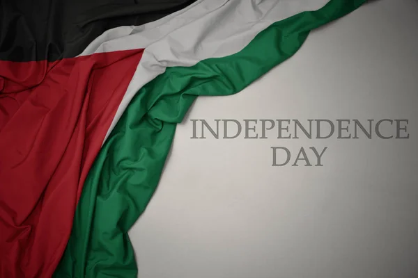 Ondeando colorida bandera nacional de Palestina sobre un fondo gris con el día de la independencia de texto . — Foto de Stock