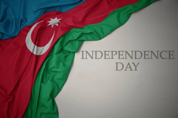 Schwenken bunte Nationalflagge von Azerbaijan auf grauem Hintergrund mit Text Unabhängigkeitstag. — Stockfoto