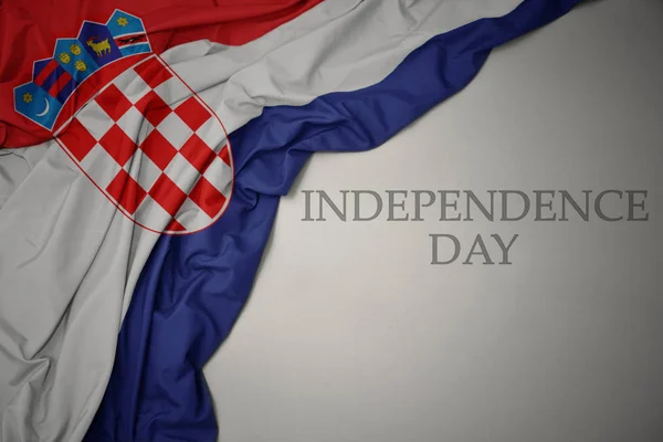 Zwaaiende kleurrijke nationale vlag van Kroatië op een grijze achtergrond met tekst Onafhankelijkheidsdag. — Stockfoto