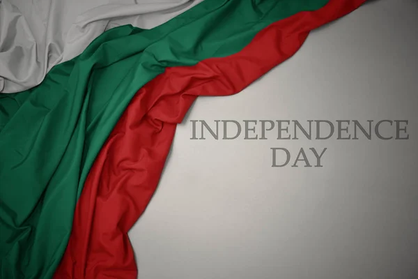 Ondeando colorida bandera nacional de bulgaria sobre un fondo gris con el día de la independencia del texto . — Foto de Stock