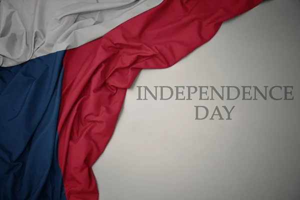 Mávat barvitá národní vlajka České republiky na šedém pozadí se dnem nezávislosti textu. — Stock fotografie