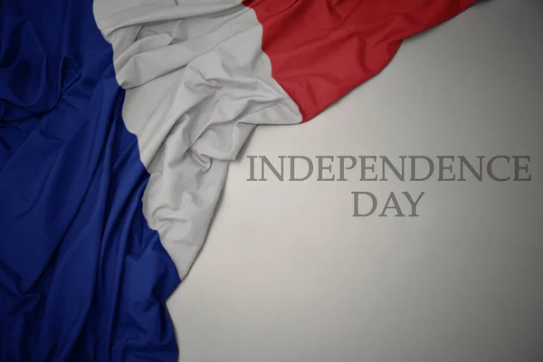 Hullámzó színes nemzeti zászló Franciaország a szürke háttér szöveges függetlenség napja. — Stock Fotó