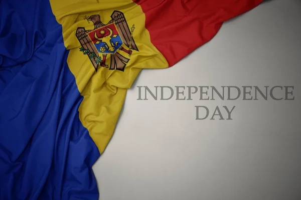 Zwaaiende kleurrijke nationale vlag van Moldavië op een grijze achtergrond met tekst Independence Day. — Stockfoto