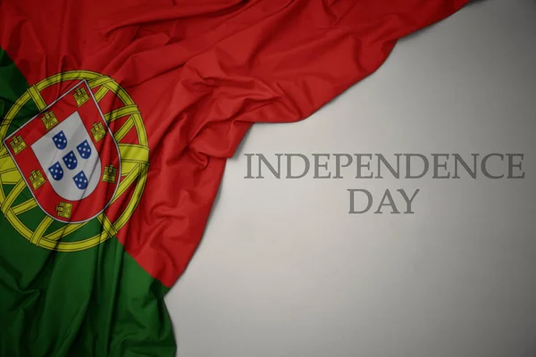Machając kolorowe flagi narodowej Portugalii na szarym tle z dniem niepodległości tekstu. — Zdjęcie stockowe