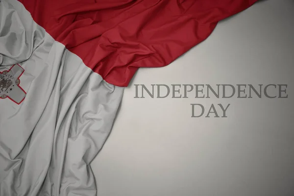 Ondeando colorida bandera nacional de malta sobre un fondo gris con el día de la independencia del texto . — Foto de Stock