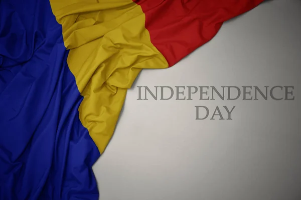 Acenando bandeira nacional colorida da Romênia em um fundo cinza com o dia da independência do texto . — Fotografia de Stock