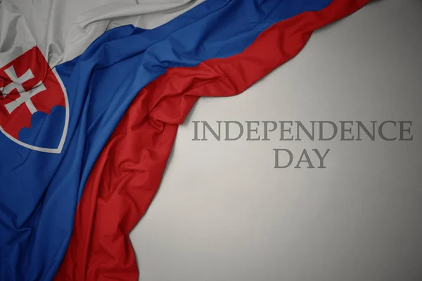 Machając kolorowe flagi narodowej Słowacji na szarym tle Dzień Niepodległości tekstu. — Zdjęcie stockowe
