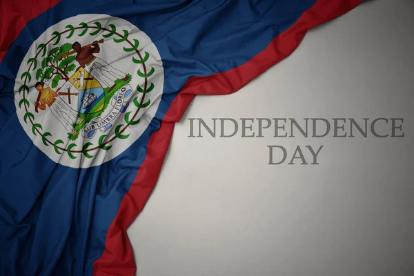 Zwaaiende kleurrijke nationale vlag van Belize op een grijze achtergrond met tekst Independence Day. — Stockfoto